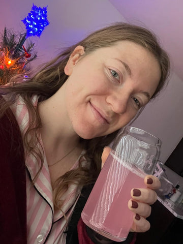 Woman sipping a pink Tavo LiquidCalm liquid calm raspberry lemonade drink as part of her evening wind-down ritual.